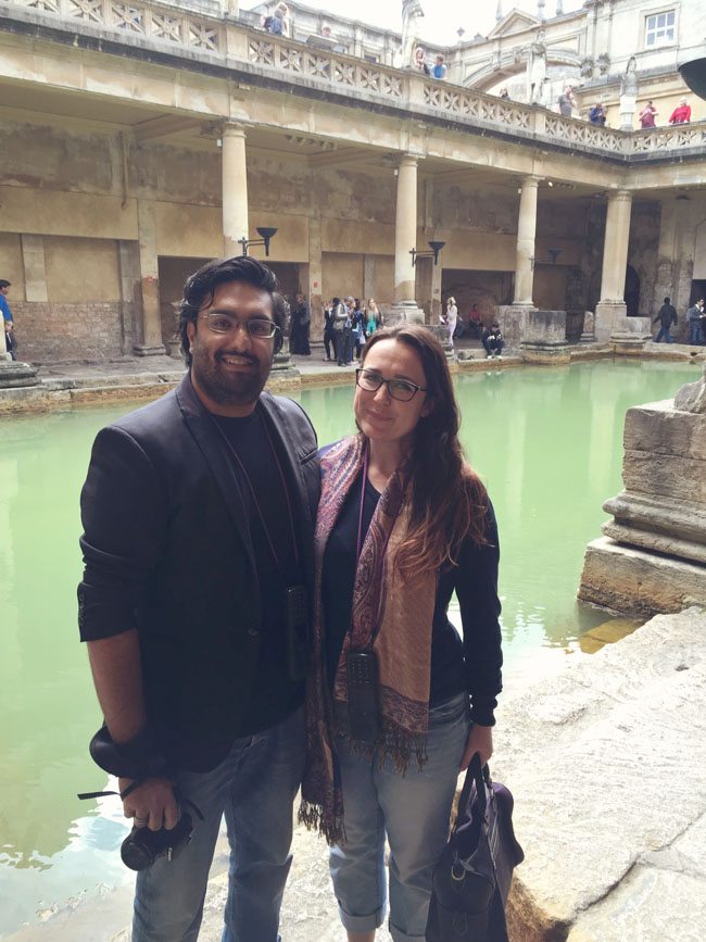 Man and woman with arms around each other in front of the roman baths in Bath