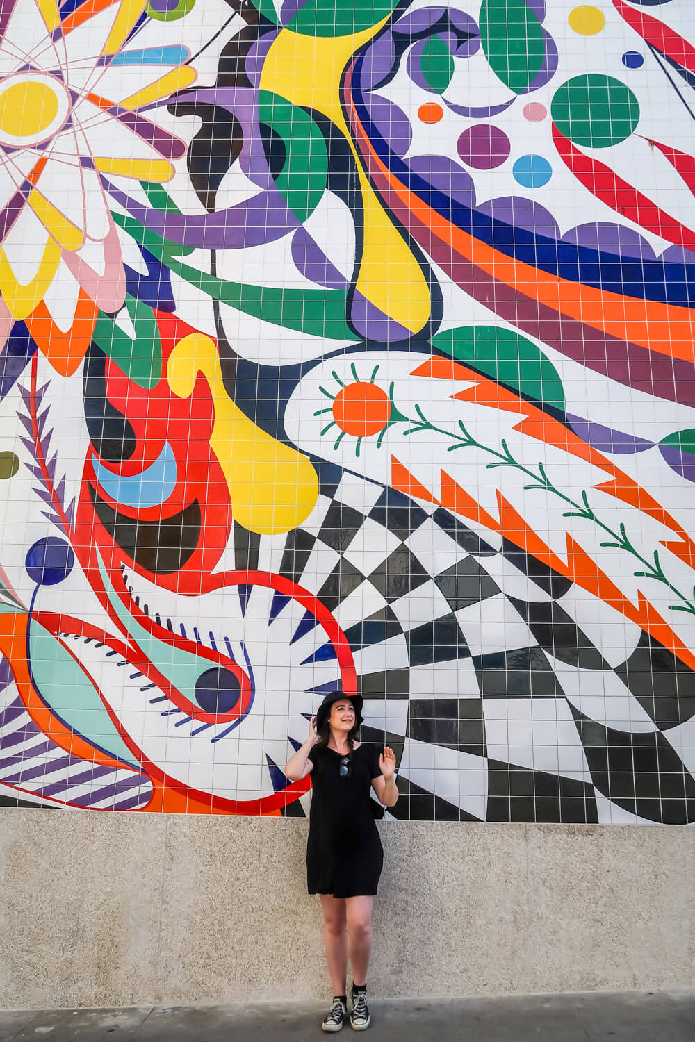 woman stands in front of huge street art mural