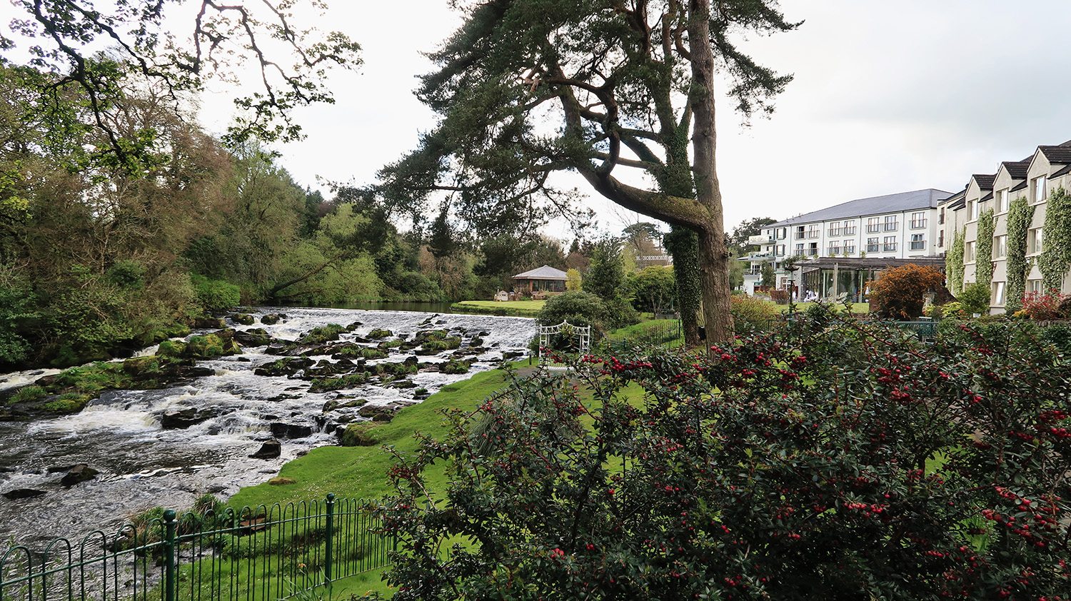 Tumbling river over rocks on the left and landscaped gardens and hotel on the right