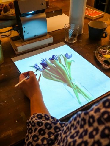 hand holds a paintbrush over project of photo onto paper