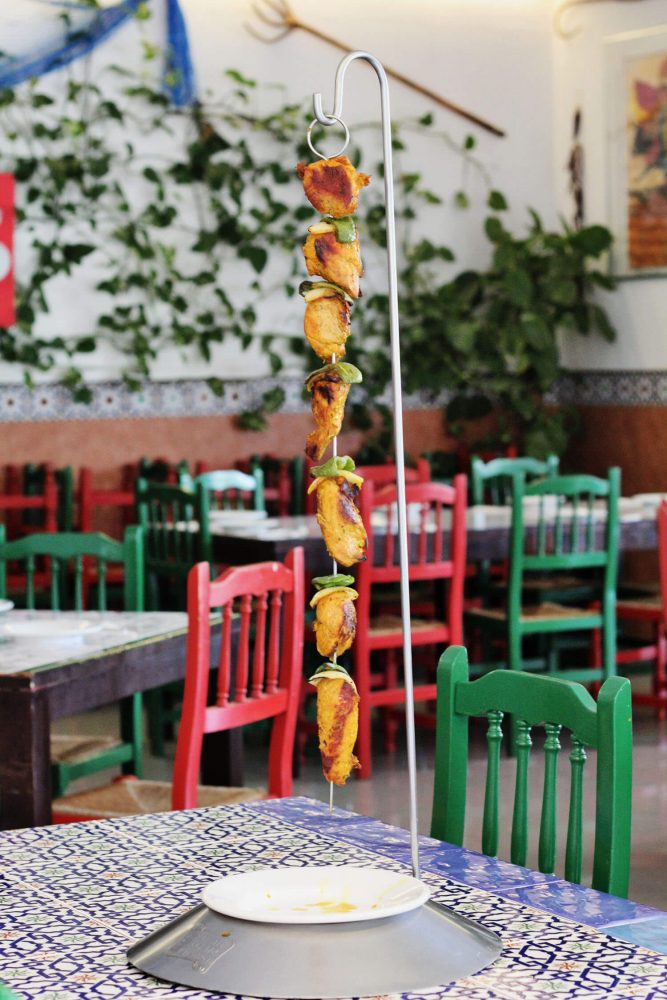 Kebab skewer hanging over plate in restaurant