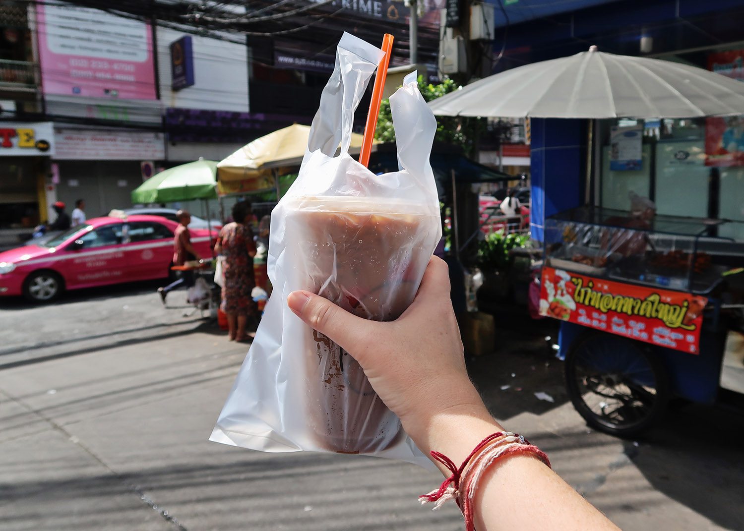 Holding a thai iced coffee in a plastic bag
