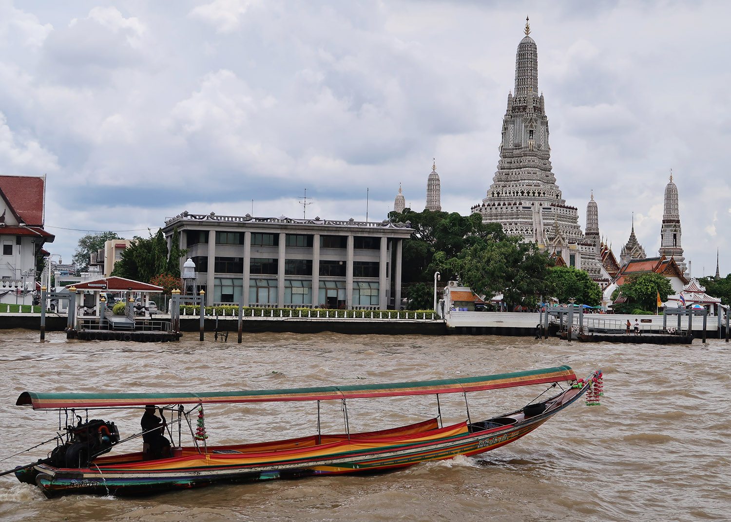 Wat Arun, a thai pagoda on the shores of a river with a small boat in the foreground