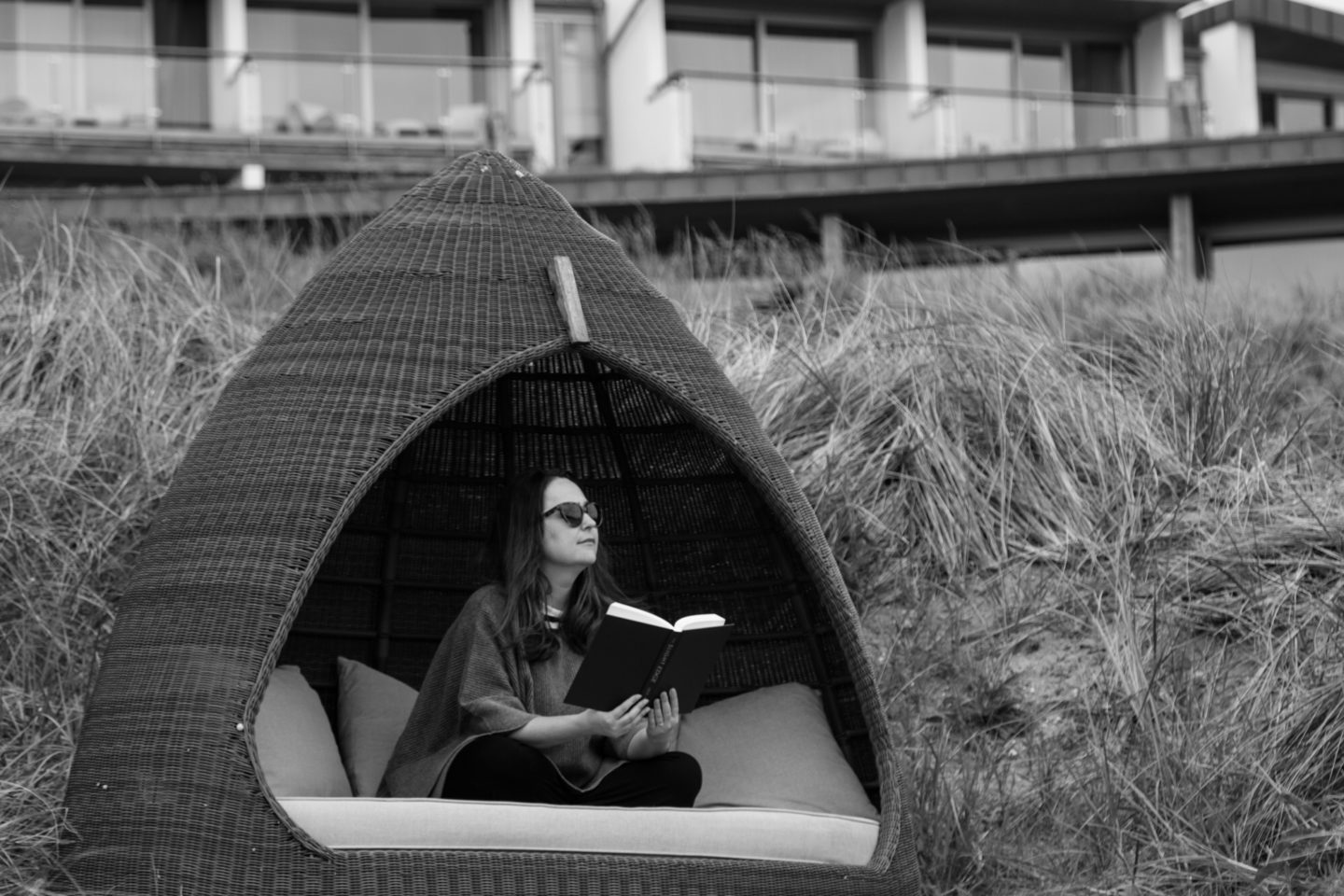 woman sits in a beach pod reading a book